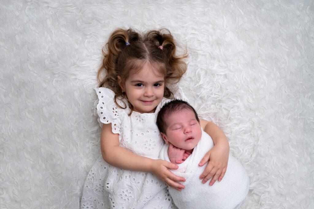 Bébé endormi dans les bras de sa grande sœur photographe nouveau-né Houilles photographe nouveau-né Yvelines photographe nouveau-né la Défense photographe nouveau-né Paris 
