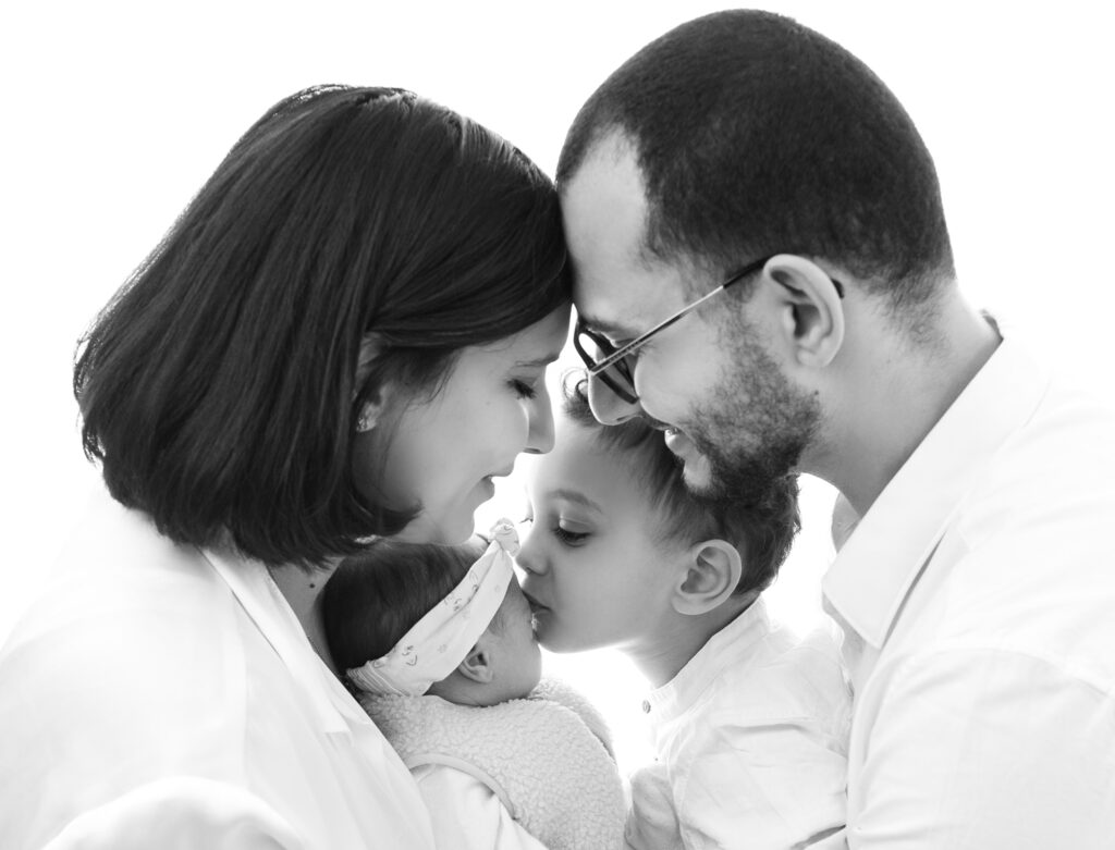 Bébé endormi dans les bras de ses parents bisou grand frère photographe nouveau-né Houilles photographe nouveau-né Yvelines photographe nouveau-né la Défense photographe nouveau-né Paris 