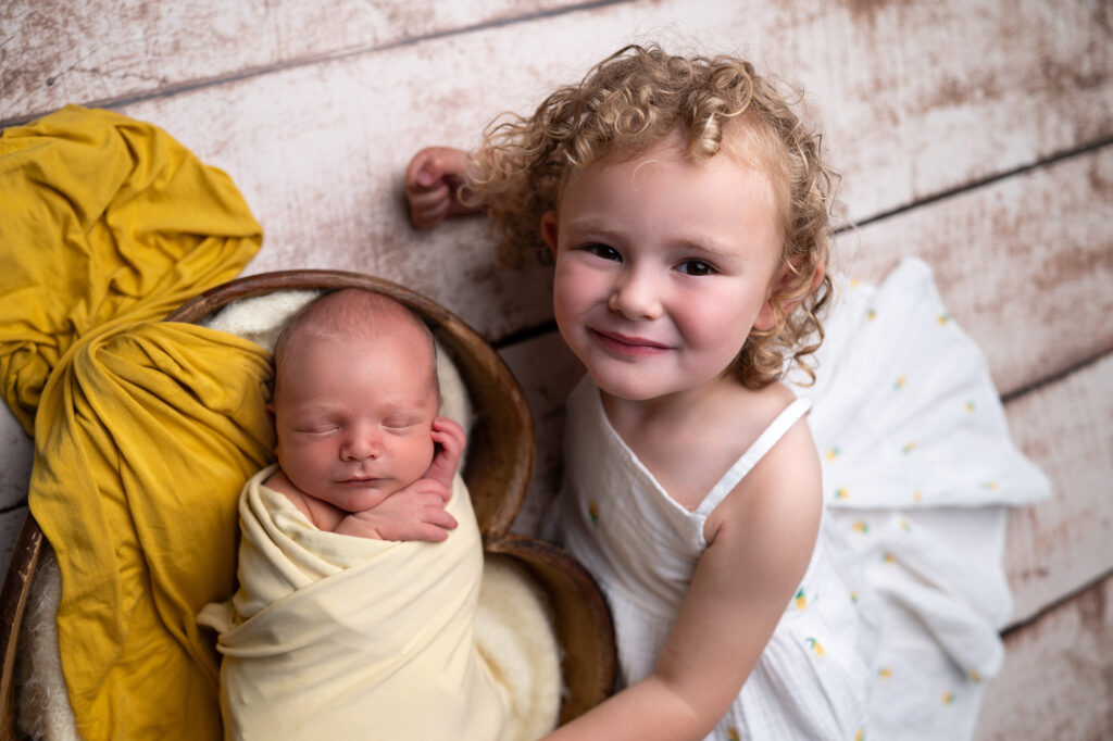 nouveau-né endormi dans un petit cœur en bois avec sa soeur photographe naissance Houilles photographe naissance la Défense photographe Houilles photographe Versailles photographe Rueil-Malmaison photographe Chatou photographe Yvelines photographe Ile-de-France