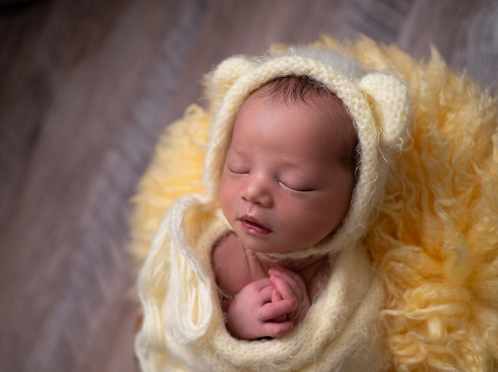 nouveau-né endormi sur fond jaune uni photographe naissance Houilles photographe naissance la Défense photographe Houilles photographe Versailles photographe Rueil-Malmaison photographe Chatou photographe Yvelines photographe Ile-de-France