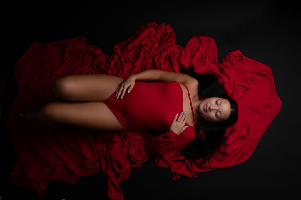 Femme enceinte body rouge allongée sur sol noir shooting grossesse Houilles Yvelines la Défense Paris
